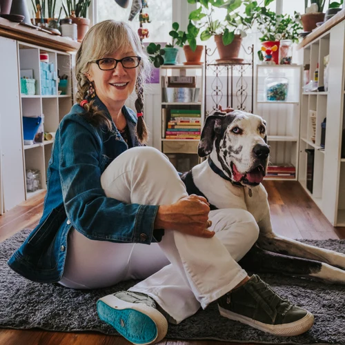 Joanne Culbreth with Vader in the Happy Moose Garden Art studio surrounded by painted planters and plants